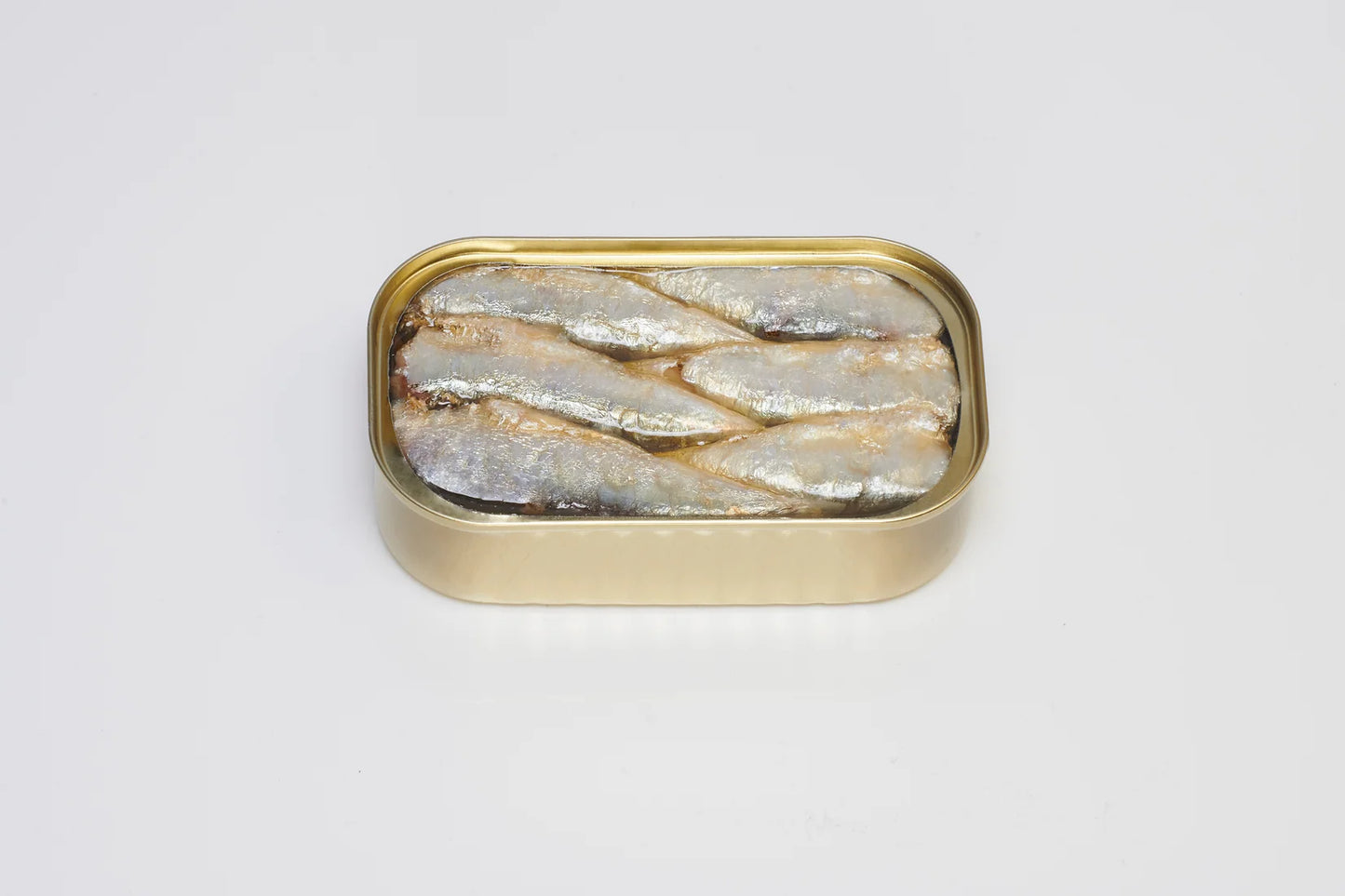 A close-up photo of a white can featuring a vintage-style label with the PYSCIS brand logo and the product name "3-Pack Sardines 'Royale' (Vintage 2019)" (SKU: SPR19). Text on the label highlights the traditional aging process (over 40 months) and the hand-packing by skilled artisans. The image showcases a single can tilted slightly forward, revealing a glimpse of several plump sardines nestled in golden olive oil through a transparent window in the can.