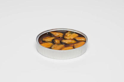 A close-up photo of an open, rectangular can of PYSCIS 3-Pack Blue Mussels with Garlic & Chili (SKU: MGP22). The can is made of metal and has a clear plastic lid that allows a view of the contents.